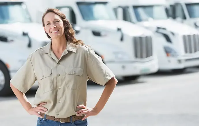 Dedicated truck driver standing in front of a fleet of trucks.